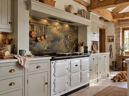 Fossil Antiqued Brass splashback above a white AGA in a farmhouse kitchen with oak beams, by Metal Clad